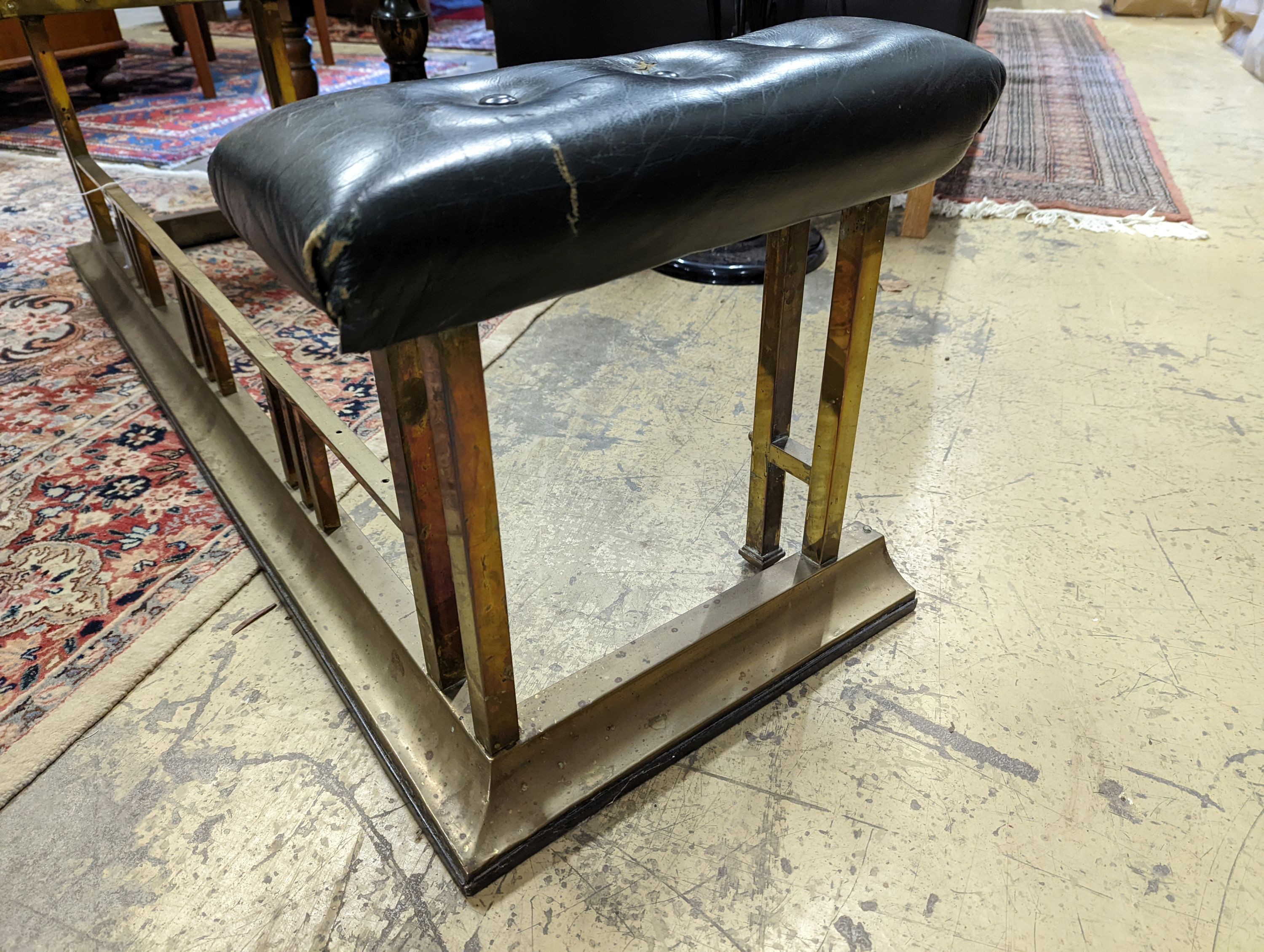 An upholstered brass club fender, width 136cm, depth 43cm, height 44cm